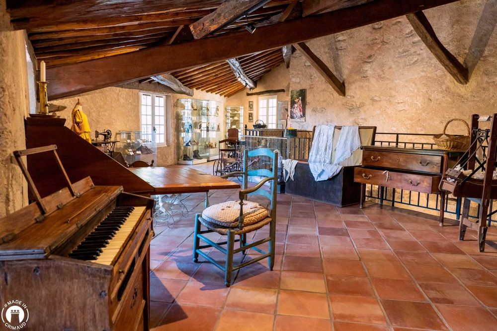 An old piano, rush-seated chairs and terracotta floor under the beams of the Musée du Patrimoine in Grimaud