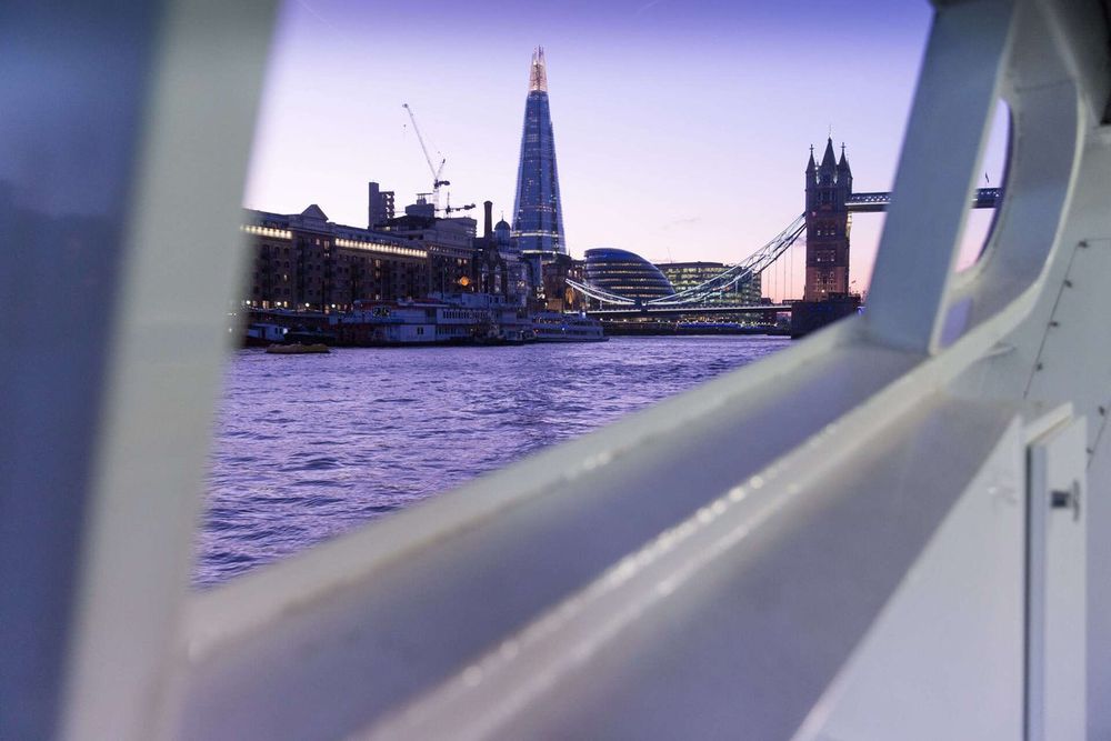 The Shard and Tower Bridge at dusk seen from the deck rail of a Thames Clippers river bus