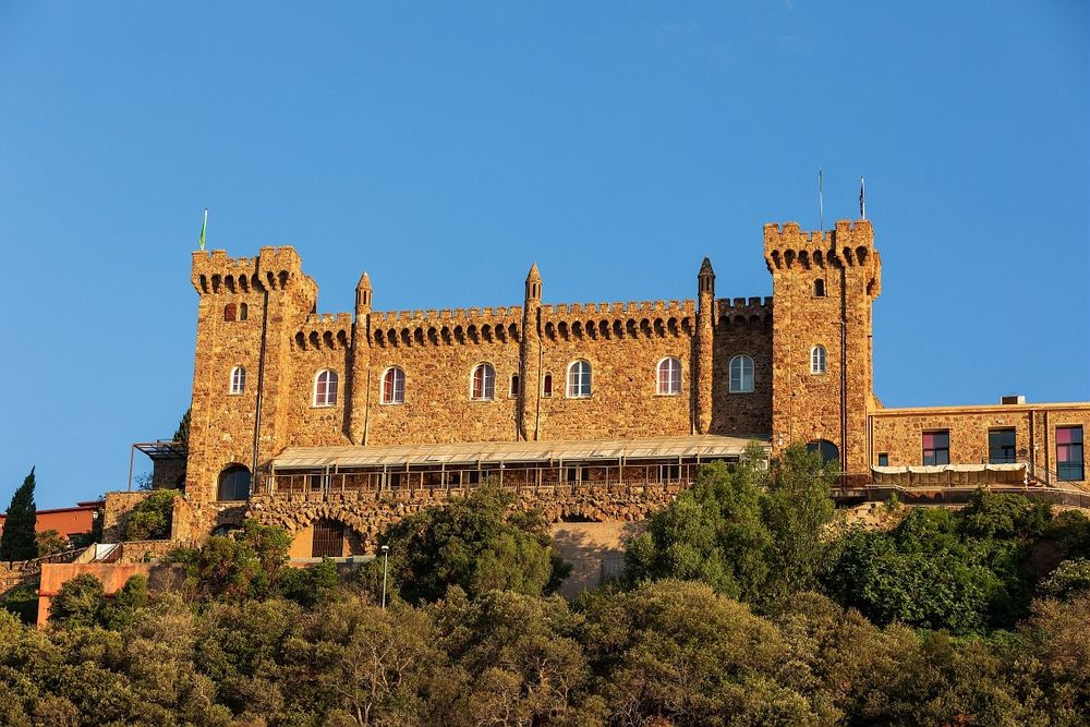 The crenellated Château d'Agecroft above the pines at La Rague under a clear blue sky