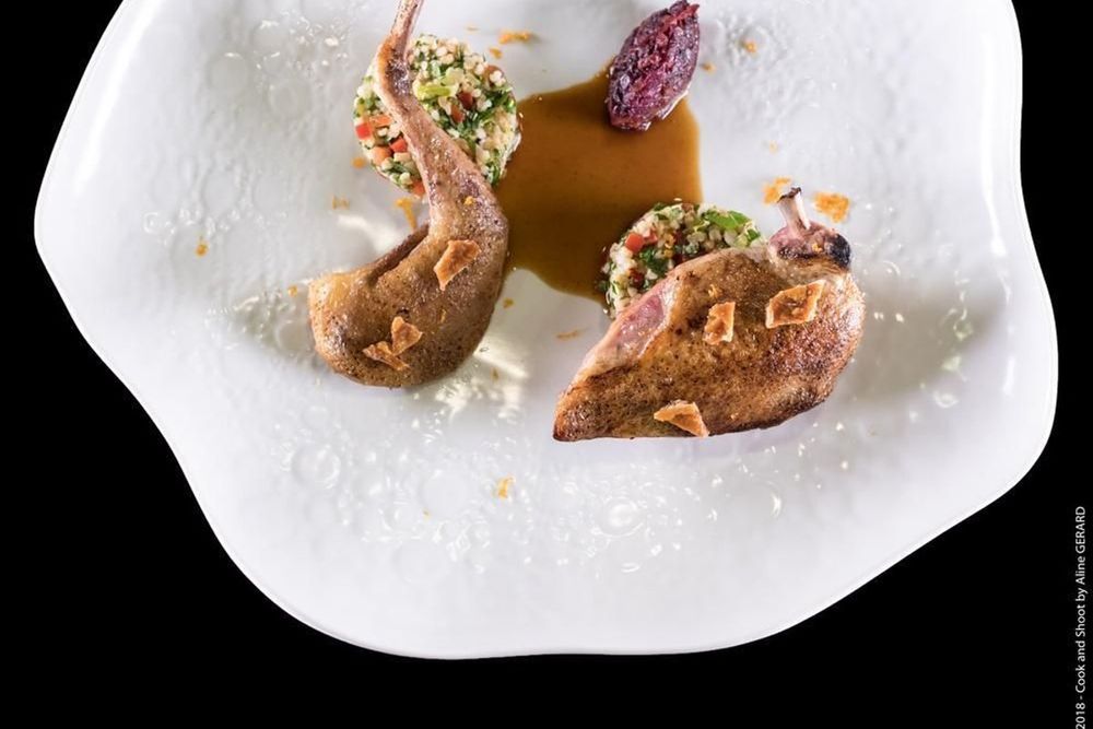 A plated dish of roast bird with herbs and a dark jus on a white plate at Bessem, Mandelieu