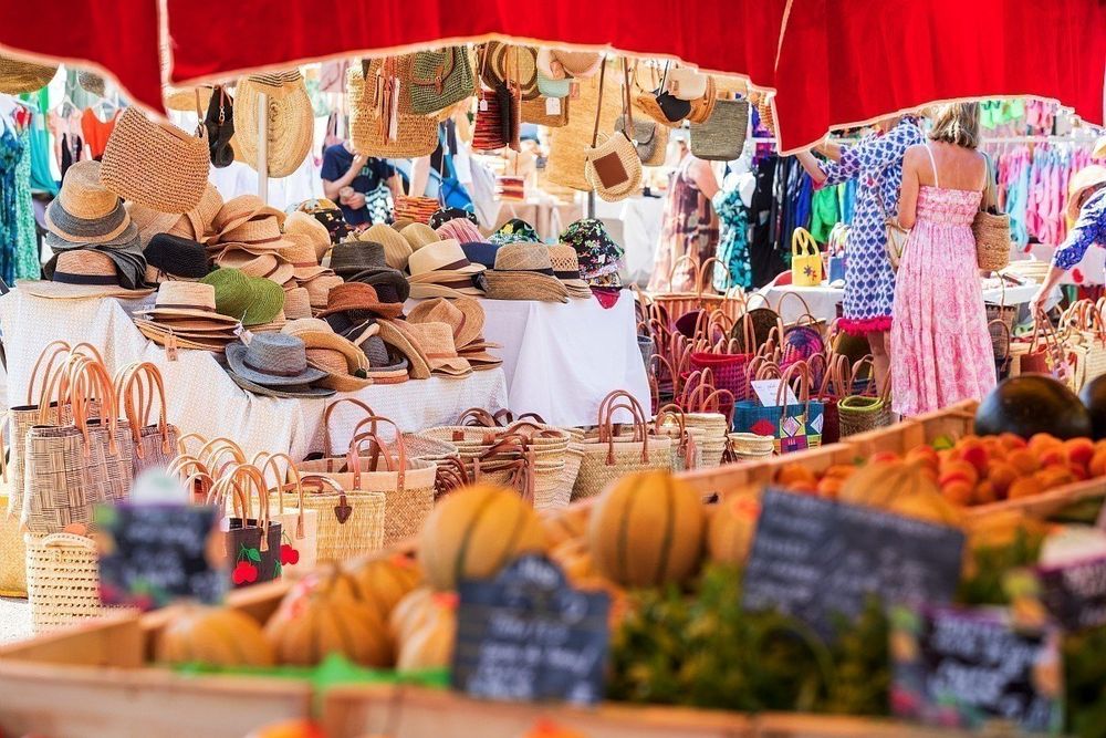 A Mandelieu market stall of straw hats, baskets and pumpkins under a red awning
