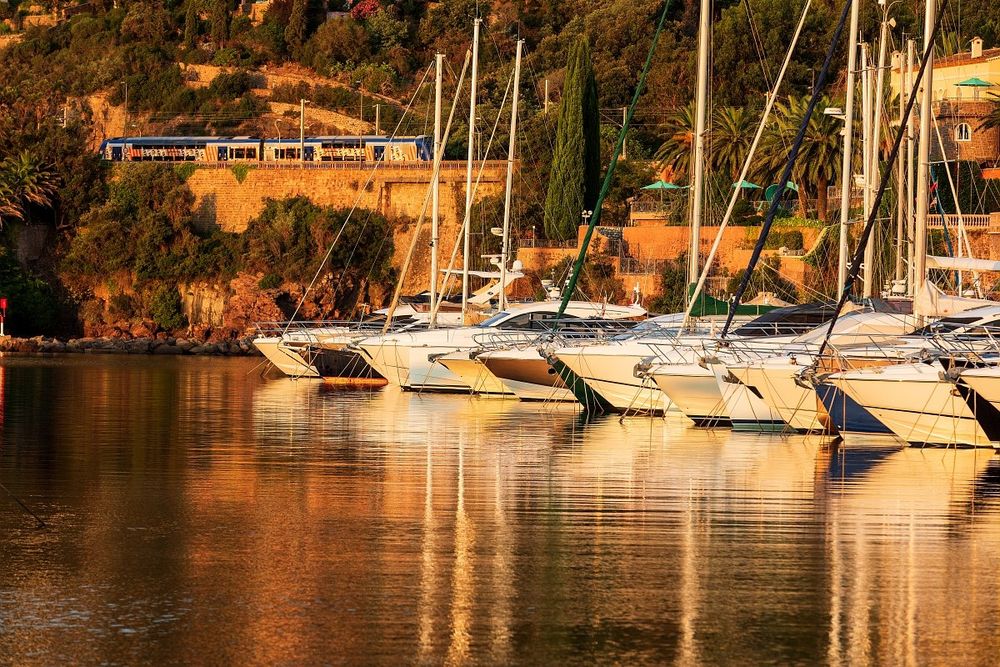 Yachts at Port de la Rague glowing in the warm light of sunset against the red rocks