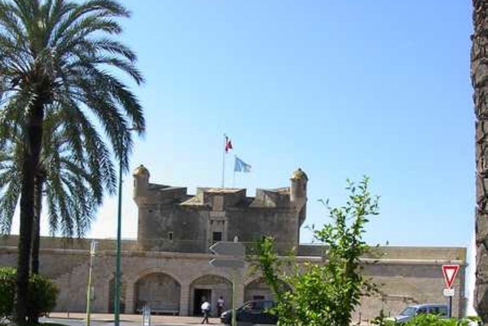 The stone Bastion of Menton, home of the Musée Jean Cocteau, framed by a palm tree