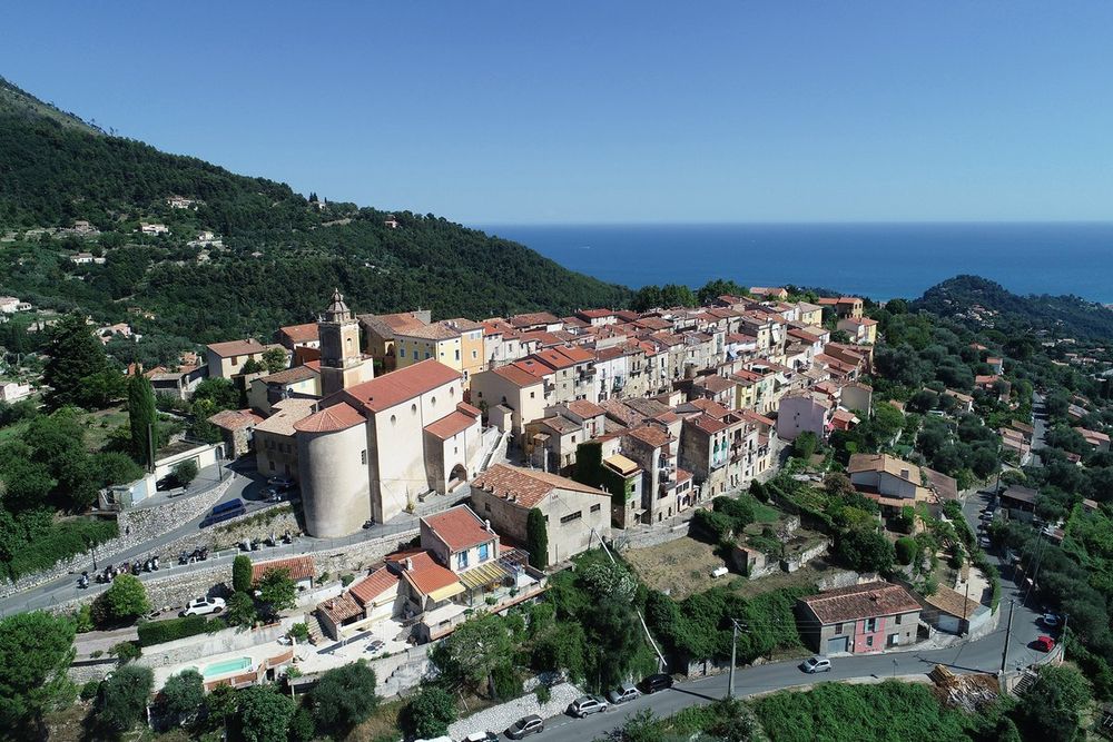 Aerial view of the perched village of Castellar on its ridge above Menton, with the sea beyond