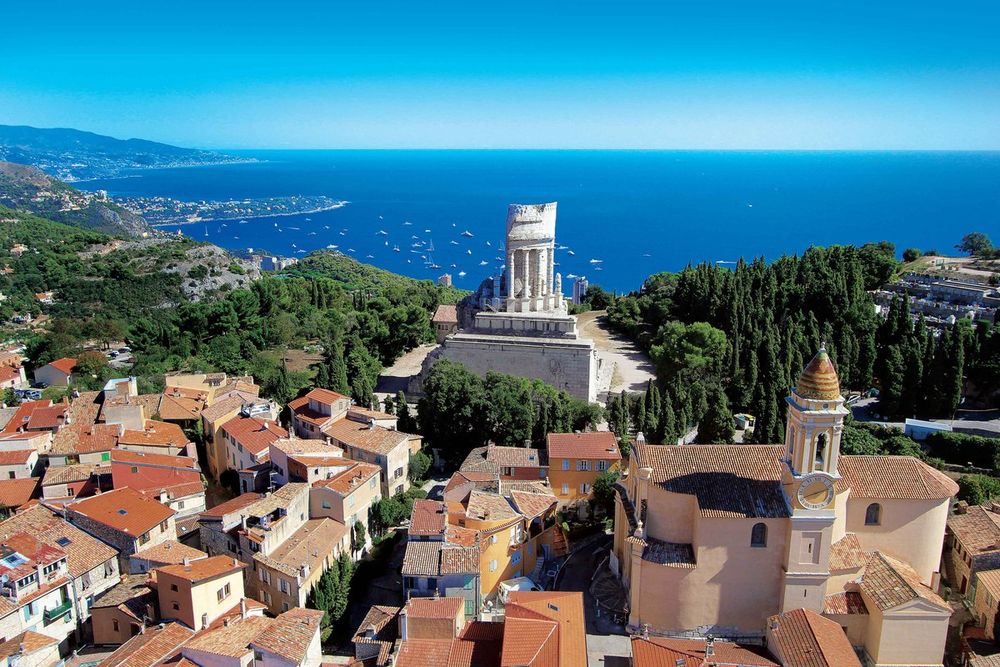 Aerial view of La Turbie's rooftops and church with the Trophée d'Auguste and the bay of Monaco behind