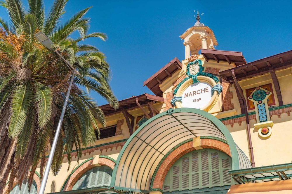 The Belle Époque façade of Menton's Marché des Halles with its ceramic 'Marché' sign and palm tree