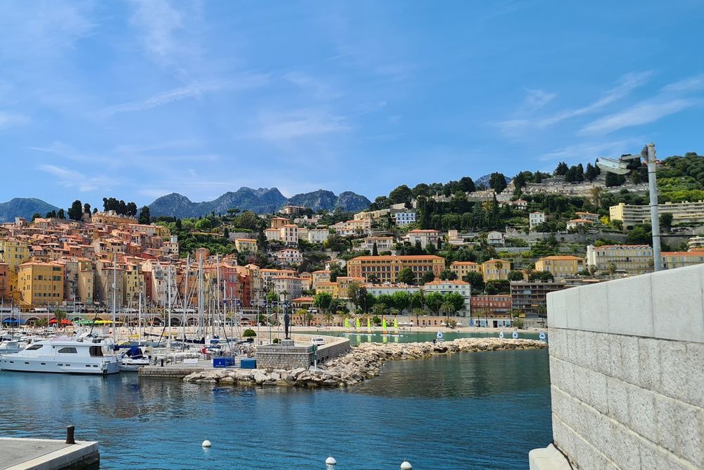 Boats in Menton's Vieux Port below the colourful old town and the mountains