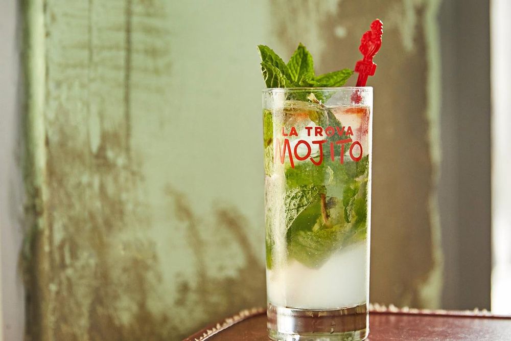 A tall mojito with fresh mint in a branded glass at Cafe La Trova