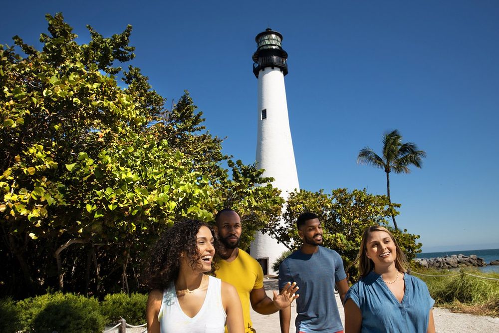 Four friends walking by the sea below the Cape Florida Lighthouse on Key Biscayne