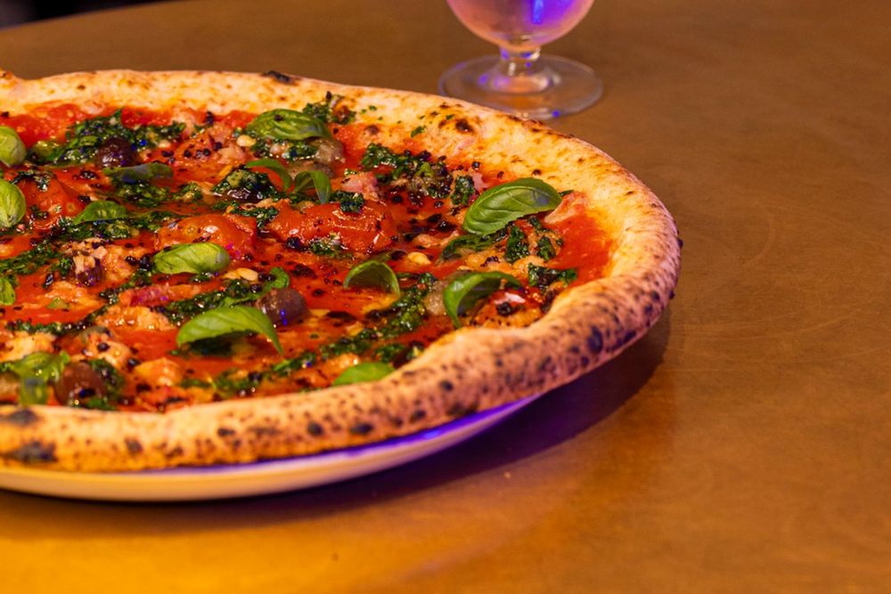 A blistered pizza topped with tomato and basil at Dry Milano