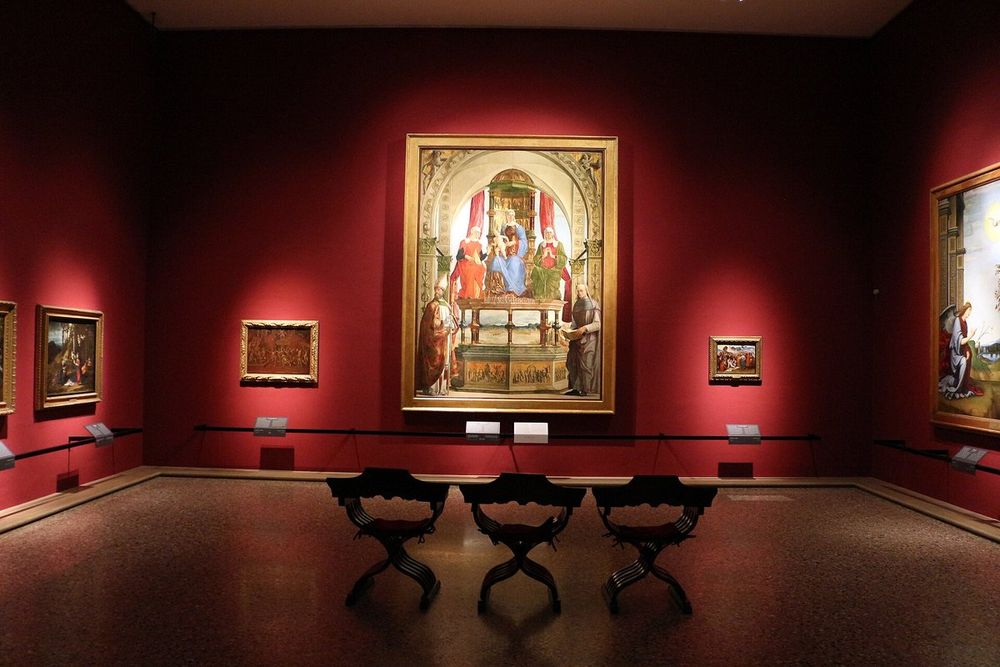 A red-walled gallery of Emilian paintings in the Pinacoteca di Brera