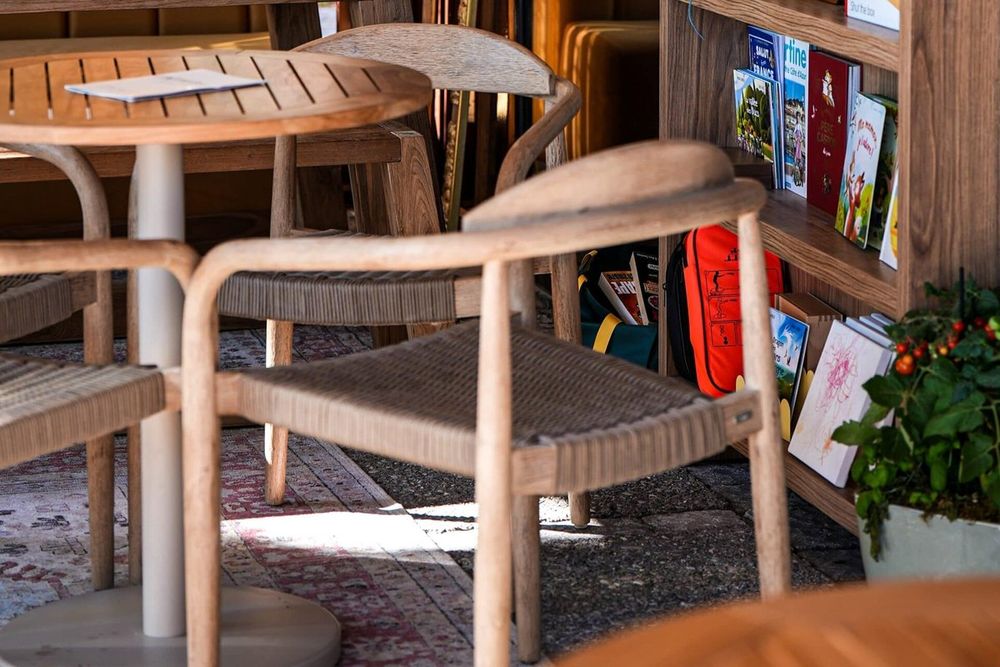 Wooden tables and a bookcase of games and books in the veranda of the Café de la Place, Mougins
