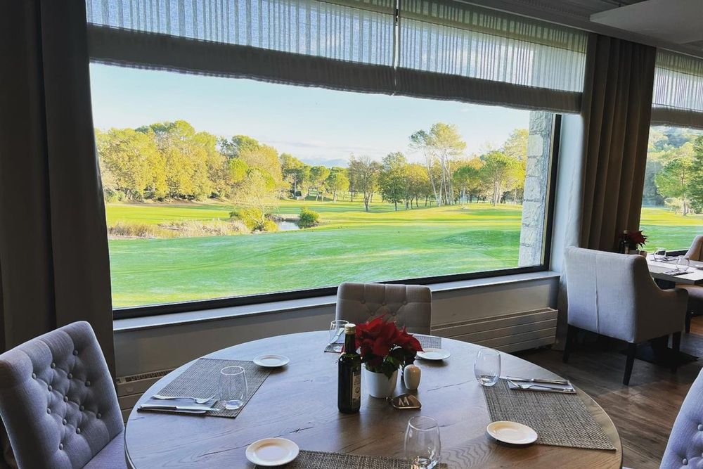 A round table by a picture window looking over the fairways of the Golf Club Cannes Mougins at Le 1923