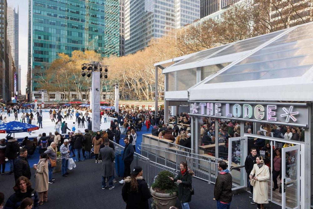 Skaters and visitors by The Lodge at Bank of America Winter Village in Bryant Park