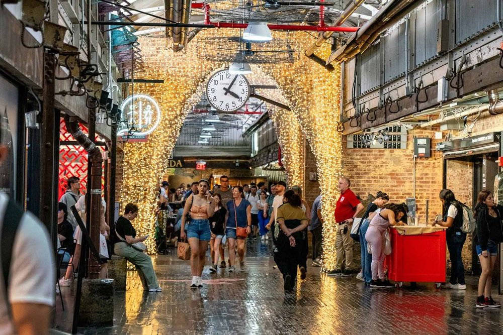The brick-arched concourse of Chelsea Market lit with string lights