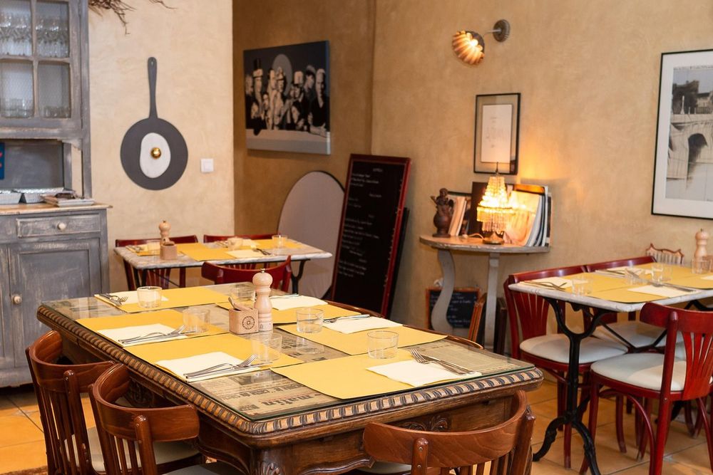 The dining room of Bistrot d'Antoine in Vieux Nice, with old tables, bentwood chairs and a chalkboard menu