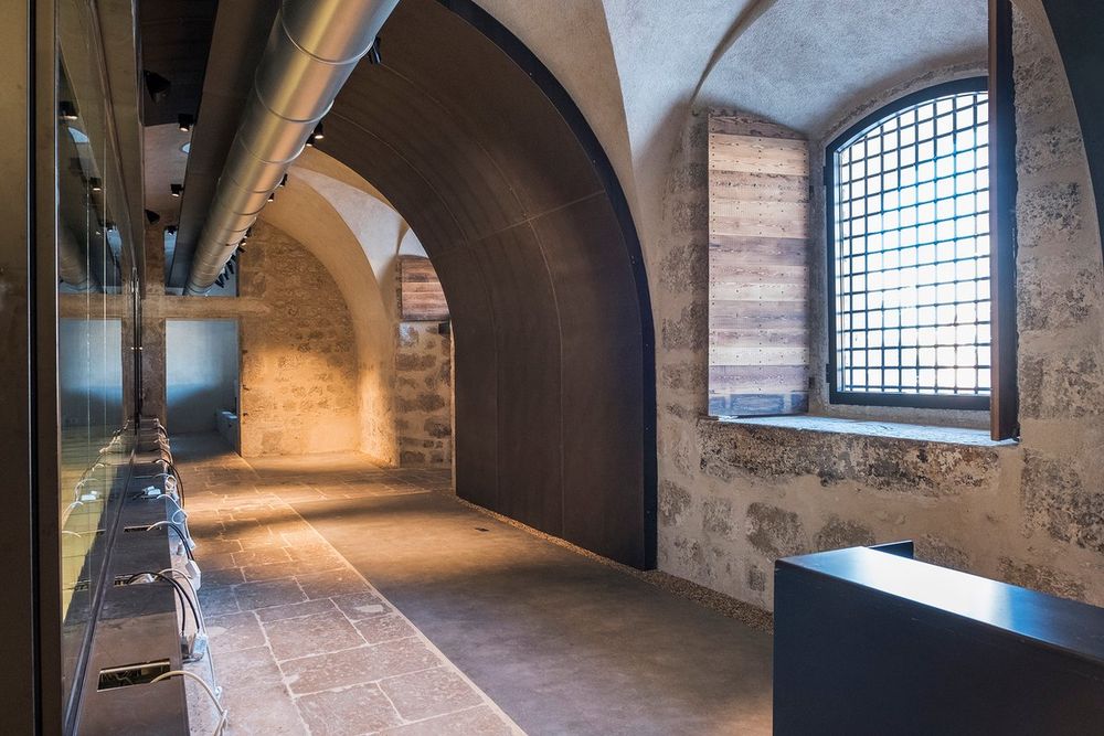 Vaulted stone corridor and barred window inside the former prison of the Espace culturel Lympia, Nice