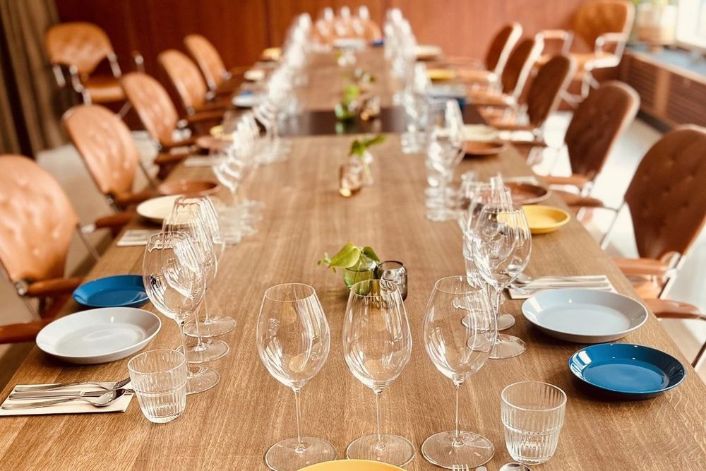 A long laid table with wine glasses and blue plates in a private room at Frances, in the former US Embassy in Oslo