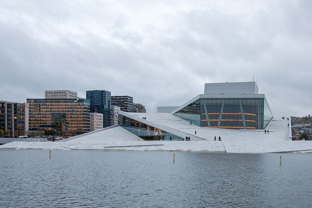The white marble roof of the Oslo Opera House rising from the water under a grey autumn sky, with Bjørvika behind