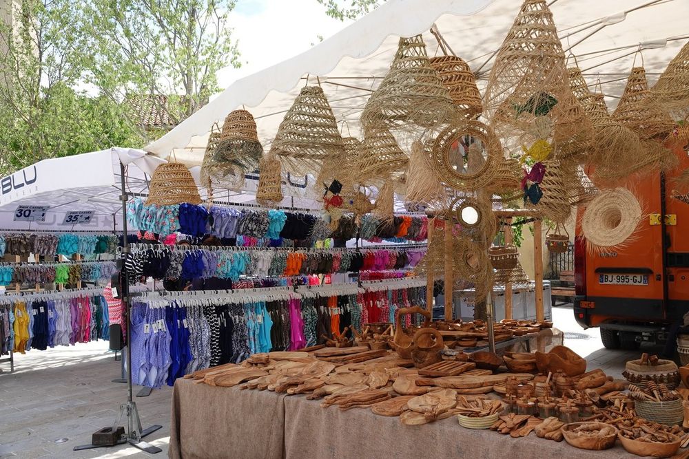 A market stall of sun hats, baskets, olive-wood bowls and beachwear at Ramatuelle market