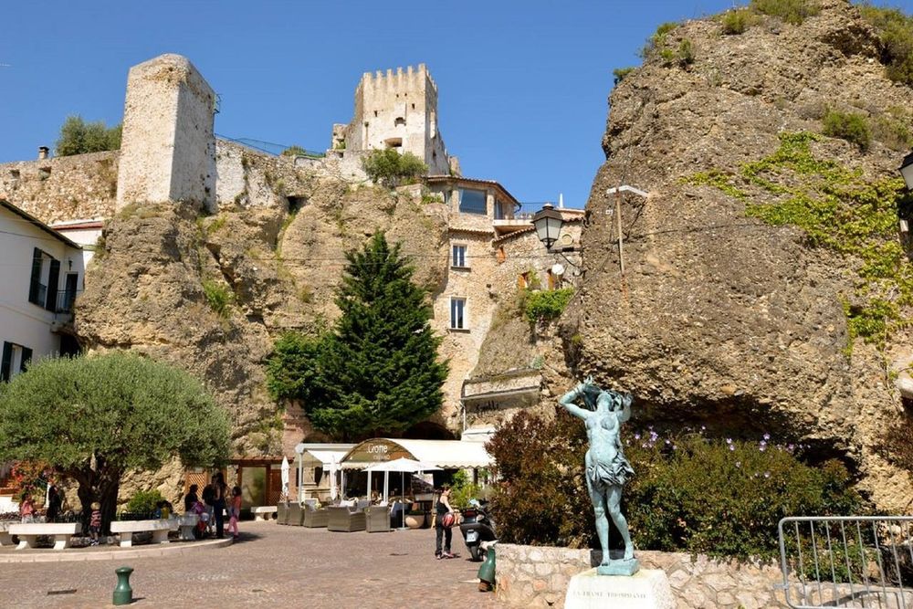 Place des Deux Frères in Roquebrune village, with the restaurant terrace of La Grotte et l'Olivier below the rock and the castle