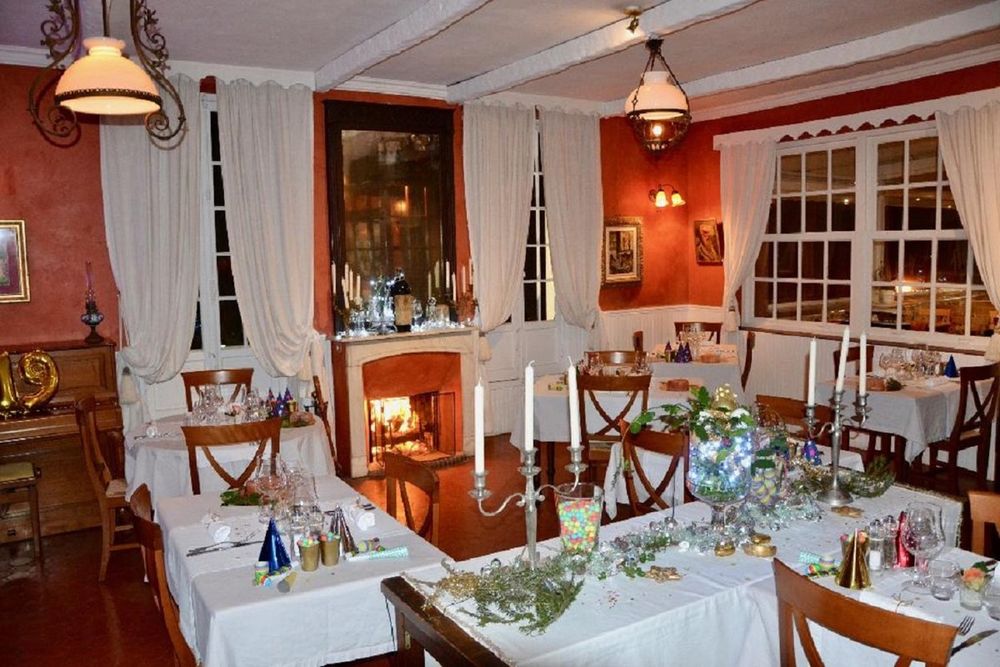 The dining room of La Roquebrunoise with a lit fireplace, candles and laid tables