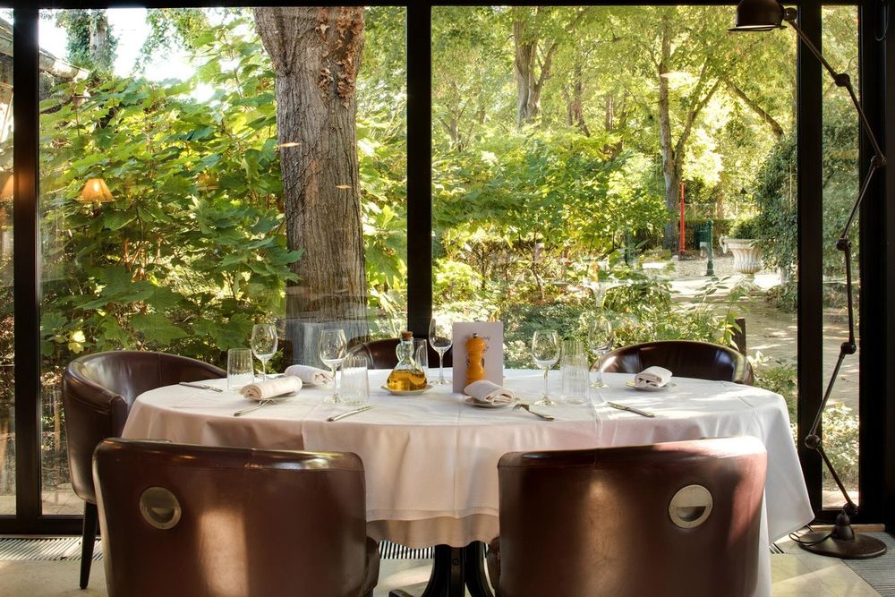A laid table in the glass-walled dining room of Cazaudehore, looking out on the trees of the forest