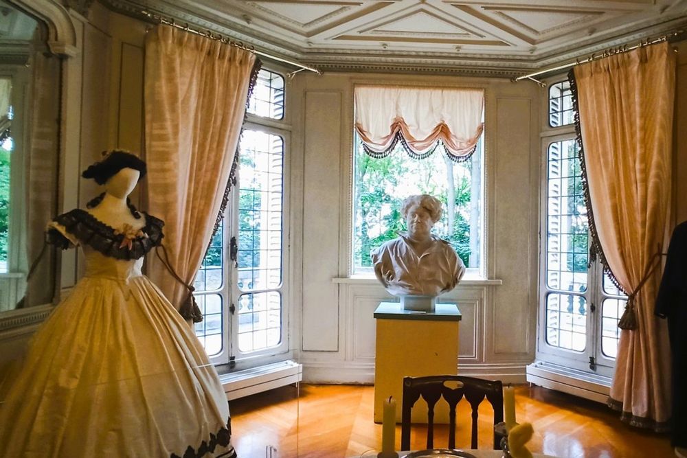 A crinoline gown and a bust of Alexandre Dumas in a bright bay-windowed room at the Château de Monte-Cristo