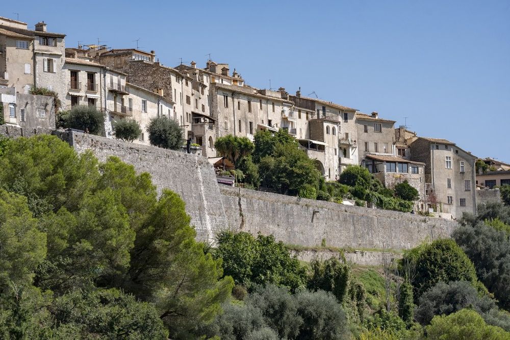 The bastioned walls of Saint-Paul de Vence rising above pines, with village houses on top