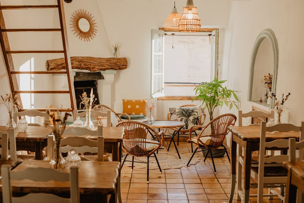 The whitewashed dining room of Café Timothé with rattan chairs and a ladder to the mezzanine