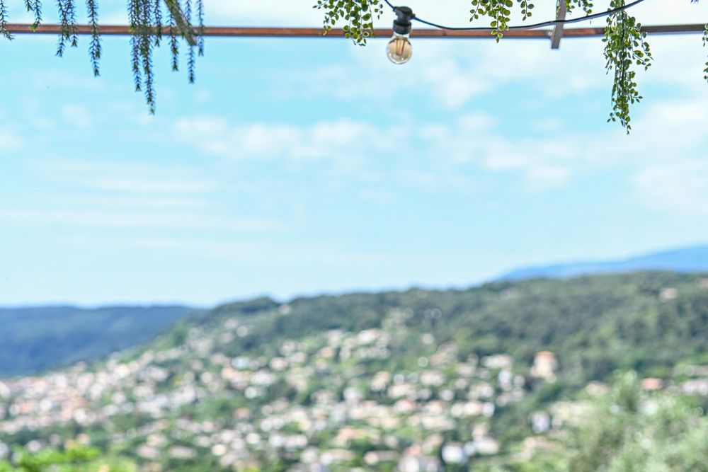 A cushioned table under the pergola at Les Remparts, looking out over the green hills