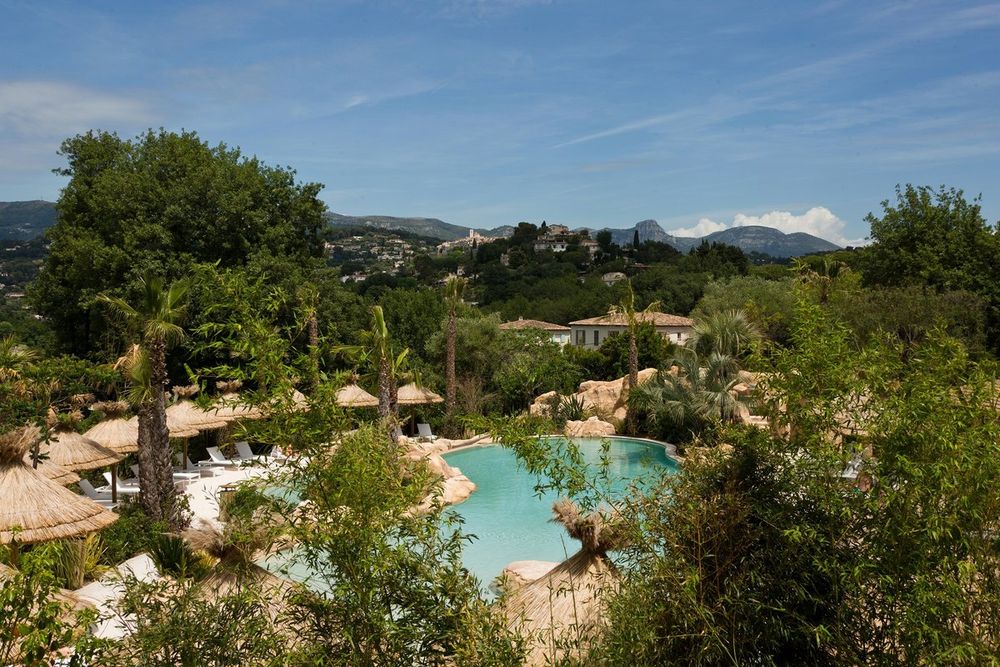 The gardens and pool of the Domaine du Mas de Pierre with hills on the horizon