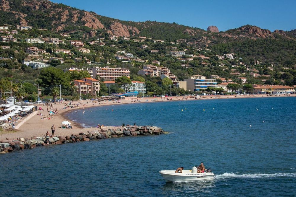 The bay of Agay with its sandy beach, villas on the hillside and the red rocks of the Estérel above