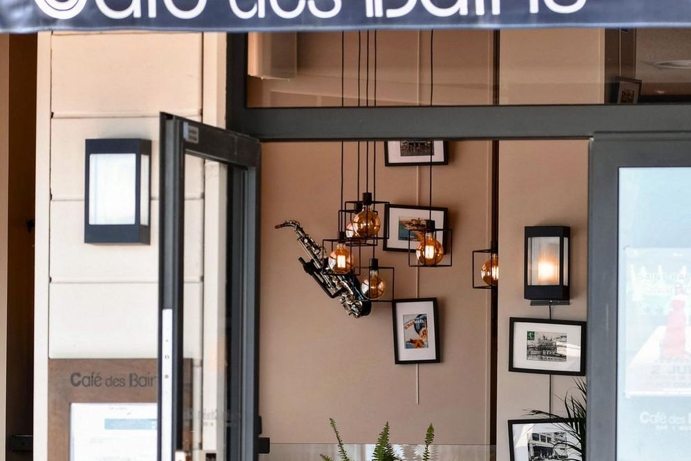 The doorway of the Café des Bains in Saint-Raphaël, with framed pictures inside and the sea beyond