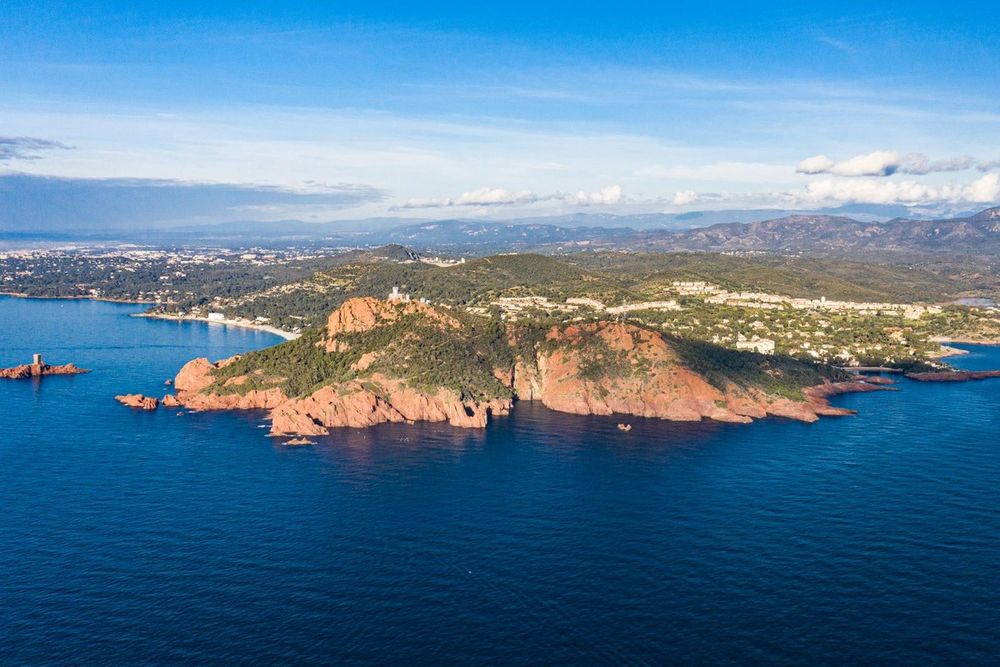 Aerial view of the red headland of Cap Dramont and the Île d'Or in a deep-blue sea