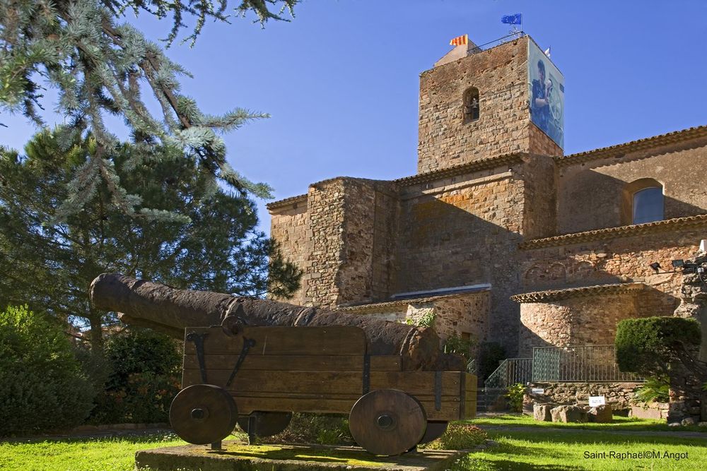 An old cannon on its carriage in front of the tower of the medieval church beside the archaeology museum