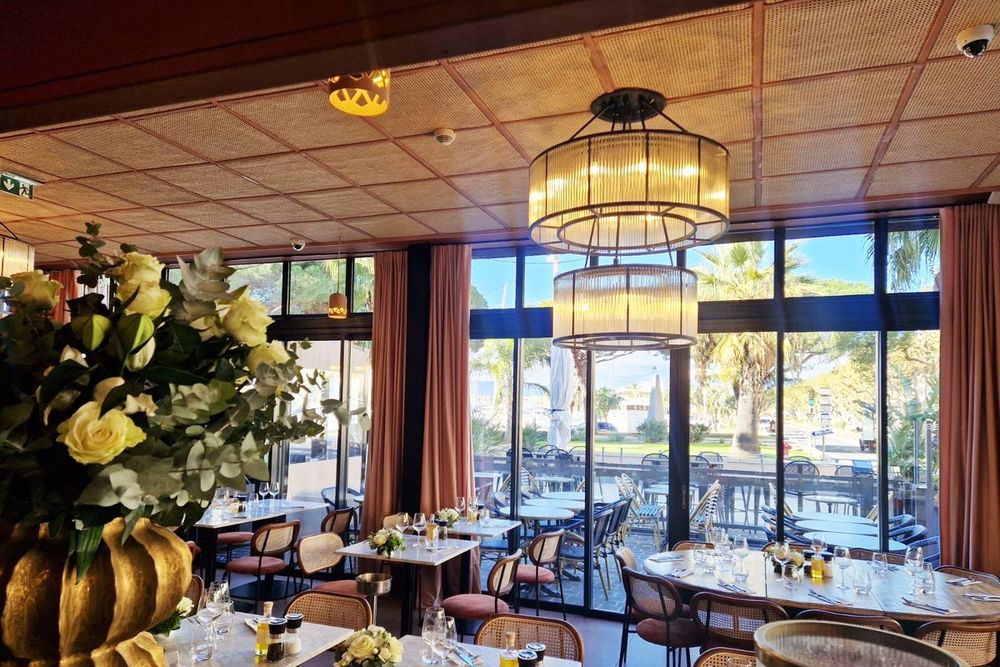 The art-deco room of Le Touring with tall windows onto the Old Port of Saint-Raphaël