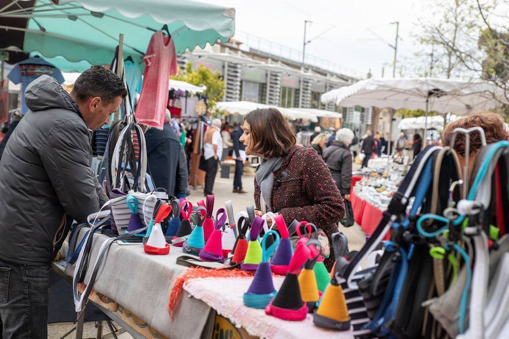 Shoppers at a stall of colourful knitted hats and bags at the Saint-Raphaël market