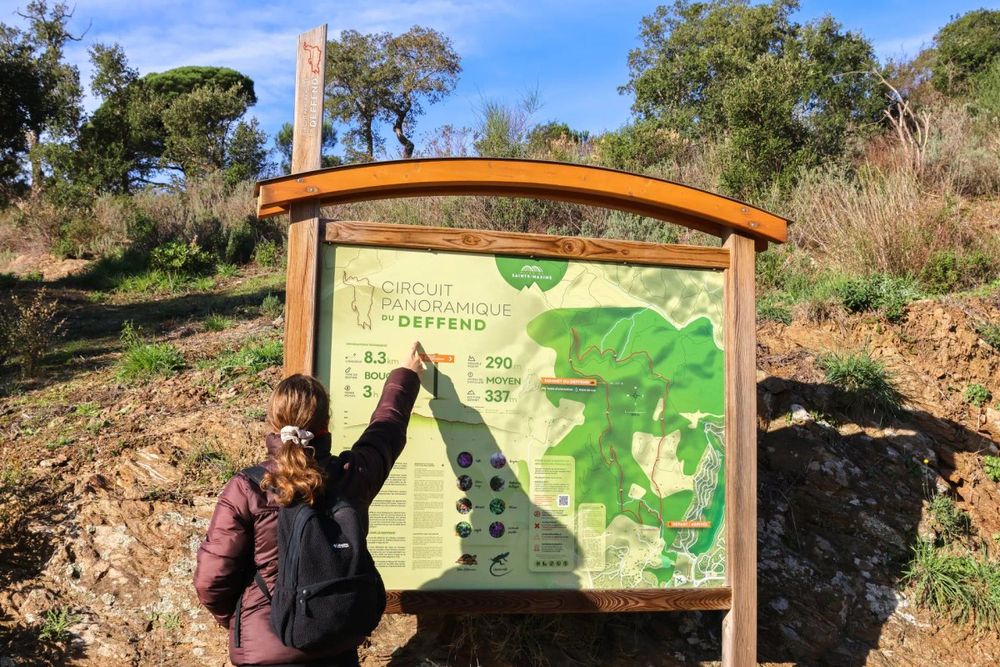 A walker pointing at the route map on the panel at the start of the Deffend trail