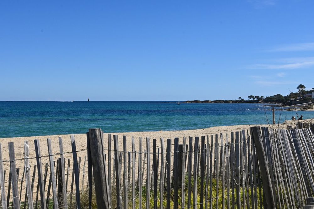 A chestnut-paling fence on the dunes of Plage de la Nartelle, the sea beyond