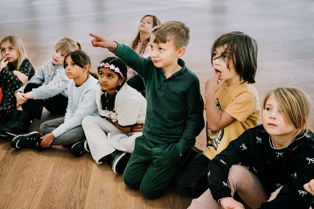 A group of children sitting on the gallery floor at Moderna Museet, one pointing at a work of art