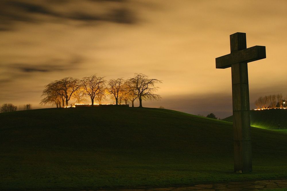 The great granite cross of Skogskyrkogården silhouetted against a glowing night sky on All Saints' weekend