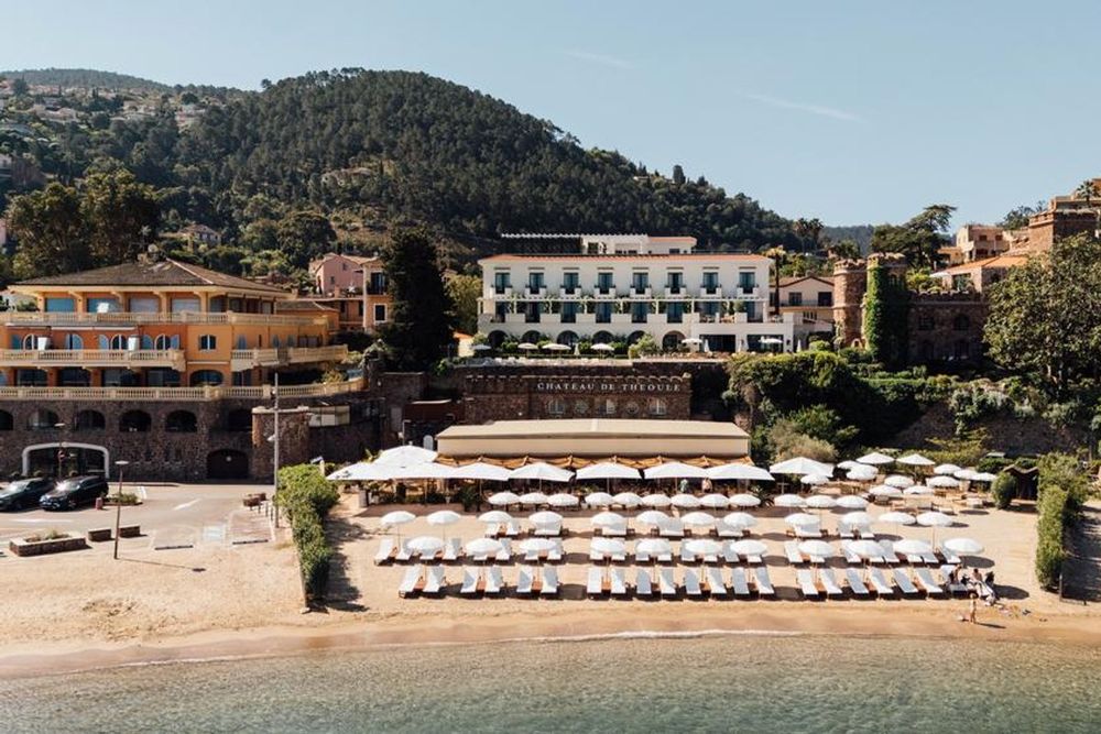 The Château de Théoule and its beach of white parasols and loungers below the green Estérel hills