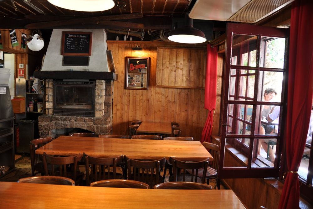 Wooden tables before the fireplace in the panelled room of Le Café Brun in Biot