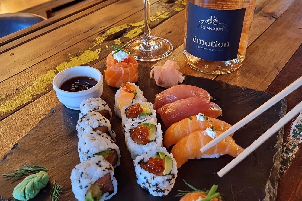 Sushi, maki and a bottle of rosé on a wooden table at La Cave du Golfe in Vallauris