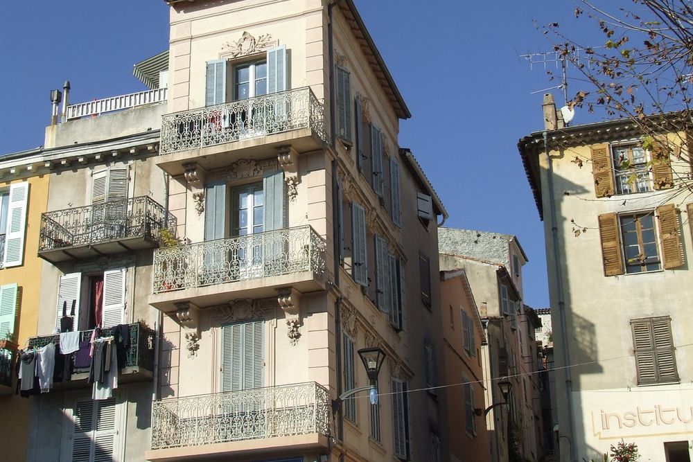 Tall old houses with wrought-iron balconies and shutters under a blue sky in the centre of Vallauris