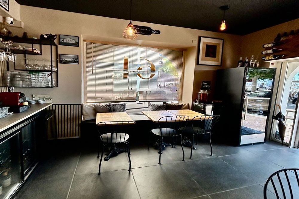 Tables by the arched window and the bar inside Le 61, bar à vin, on Golfe-Juan's Vieux Port