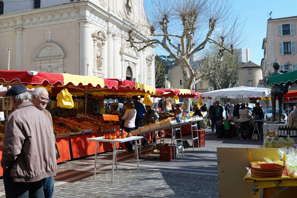 Shoppers at the produce stalls of the morning market in front of the church in Vallauris's old town