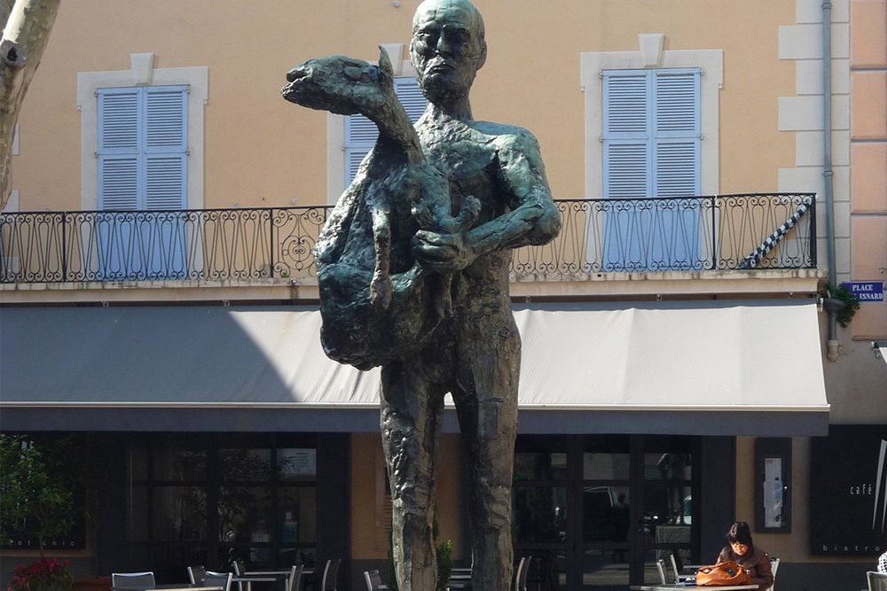 Picasso's L'Homme au Mouton standing before café awnings and balconied houses on Place Paul Isnard, Vallauris